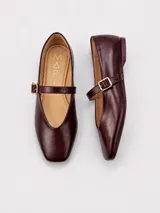 Zapato flat tipo Mary Jane de ecocuero negro, con puntera cuadrada, suela baja y tira en el empeine con hebilla metálica.