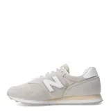 Championes New Balance modelo 373 para mujer, color gris claro y beige, con detalles en blanco y cordones blancos. Presentan una combinación de gamuza y malla.