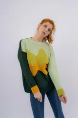 Sweater de lana merino verde con diseño de paisaje abstracto en tonos verde claro, amarillo y naranja.
