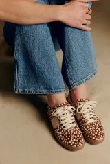 Zapatilla de cuero con textura de pelo y estampado animal print de puntos, con detalles en cuero liso color crema en los laterales y talón, y suela de goma color caramelo.