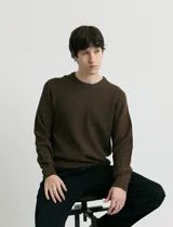 Sweater de punto con textura en color verde oscuro, de cuello redondo y manga larga.