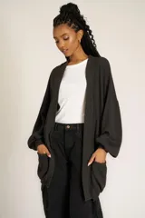 Cárdigan negro de tejido de punto con diseño holgado, cuello y puños acanalados, bolsillos laterales y mangas largas abullonadas.