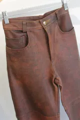 Pantalón de cuero napa color marrón, de tiro alto y corte recto, con bolsillos delanteros y traseros.