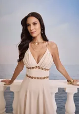 Vestido largo color beige, con breteles finos y escote en V. Presenta detalles de argollas doradas en la cintura y en el busto.