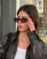 Lentes de sol unisex con montura ovalada negra y cristales marrones.