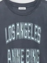 Remera gris oscura de algodón con calce amplio, cuello redondo y estampa tipográfica frontal estilo universitario en tonos claros.