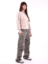 Buzo de punto color beige claro, con cuello alto, mangas largas tipo murciélago y puños ajustados. El bajo del buzo es ajustado y cruzado.