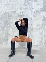 Short de tiro alto confeccionado en tela tipo gamuza scuba, con detalle de cordones frontales cruzados y ojales metálicos. Presenta un diseño ajustado y elástico que se adapta a la silueta.