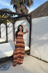 Vestido largo strapless, ajustado al cuerpo, con estampado batik en tonos marrones y naranjas.