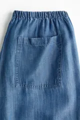 Pantalón de denim liviano, color azul, con cintura elástica y cordones ajustables en los tobillos.