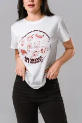 Remera de algodón blanca con cuello redondo y mangas cortas. Presenta un estampado frontal en color bordó con ilustraciones de cristales y frases motivacionales.