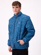 Campera reversible de nylon con cuello alto y cierre frontal. Un lado es de color gris liso con logo bordado, mientras que el otro lado presenta un estampado abstracto en tonos azules. Cuenta con bolsillos laterales y puños elásticos.