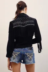 Short de denim azul de tiro bajo, con lavado desgastado, dobladillo desmechado y bolsillos traseros con bordados ornamentales y tachas metálicas.