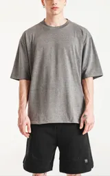 Remera de corte amplio y relajado, con hombros caídos y largo a la altura de la cadera. Confeccionada en algodón premium de color gris melange, con cuello redondo clásico.