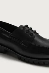 Zapato náutico de piel color negro, con cordones y suela dentada tipo track.