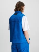 Chaleco acolchado azul eléctrico con cierre frontal, cuello alto y logo de Calvin Klein en el pecho.