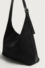 Bolso de hombro tipo shopper en color negro, con diseño liso y cierre magnético. Cuenta con un bolsillo interior con cremallera y asa ajustable.