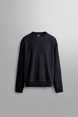 Buzo negro de cuello redondo, corte relaxed fit, confeccionado en tejido de algodón con interior de rizo y acabado en rib.