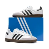 Championes Adidas Samba OG blancos con tres tiras negras a los costados y suela marrón de goma.
