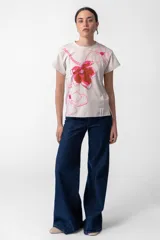 Remera color crudo de algodón con cuello redondo y mangas cortas. Estampa exclusiva "Flower Market" con flores en tonos rosa y marrón.