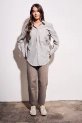 Camisa oversize color arena con rayas verticales marrones, de manga larga y cuello clásico.