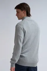 Buzo de punto gris claro melange con cuello alto y medio cierre.