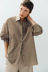 Camisa de popelina a rayas marrones, blancas y celestes, con cuello clásico, manga larga, bolsillo frontal de parche y cierre de botones.