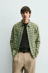 Camisa de corte relajado confeccionada en tejido de algodón con estampado de cuadros en tonos verdes y beige. Presenta cuello solapa, cierre frontal con botones a presión, bolsillos plastrón en el pecho y mangas largas con puños abotonados.