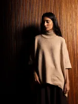 Polerón negro de tejido de punto con cuello alto, diseño oversized, mangas 3/4 y corte asimétrico más largo en la parte posterior.