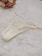 Tanga de encaje color champagne con diseño floral bordado, breteles finos regulables y terminaciones delicadas.