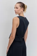 Chaleco sastrero de corte entallado, con diseño sin mangas y ajuste mediante hebilla metálica en la parte posterior.