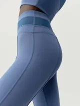 Legging flare largo de color negro, confeccionado en tejido Skin_Move. Presenta cinturilla ancha de doble tejido y un panel decorativo de malla transpirable en el centro del torso.