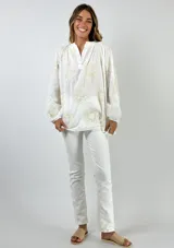 Blusa blanca de corte holgado con mangas tres cuartos abullonadas, cuello mao con pequeña abertura frontal y bordados florales en hilo dorado.