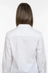 Camisa clásica de corte recto y largo cropped, confeccionada en algodón. Presenta cuello camisero tradicional, cierre frontal con botones y mangas largas con puños anchos.