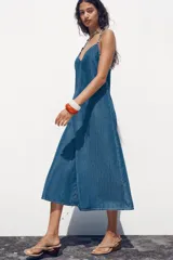 Vestido midi de denim azul, con escote en pico y tirantes finos.