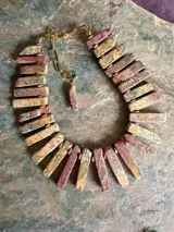Collar corto elaborado artesanalmente con piezas rectangulares de jaspe en tonos ocre, rosa viejo y bordeaux, con cadena de eslabones y cierre ajustable.