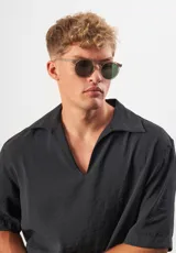 Lentes de sol redondos con montura gris translúcido y lentes verdes. Fabricados con acetato biodegradable y lentes de PMMA reciclado.