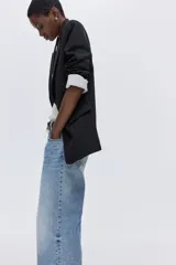 Blazer de sarga con solapas de pico, diseño de frente abierto y bolsillos delanteros ribeteados con solapa. Presenta mangas diseñadas para ser remangadas, dejando a la vista un forro interior a rayas.