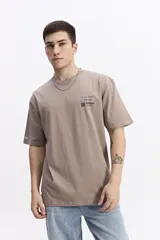 Remera de manga corta color topo, con escote redondo y fit regular. Presenta un pequeño estampado en el pecho con texto manuscrito y un código QR.