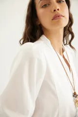 Camisa de algodón celeste con cuello mao, pechera con botones ocultos y mangas abullonadas con puños elásticos.