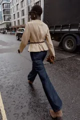 Chaqueta de cuello redondo y manga larga con diseño peplum en el bajo. Confeccionada en tejido efecto ante, cuenta con cierre frontal de cremallera y cinturón fino ajustable en la cintura.