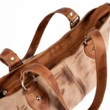 Cartera tipo shopper de cuero color marrón tostado, con doble asa de hombro, costuras decorativas centrales, detalles de tiras laterales con hebilla y un parche de cuero con logo grabado en la parte frontal.