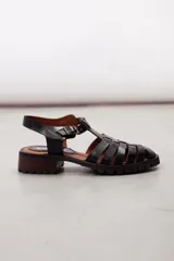 Sandalias de cuero color negro, tipo cangrejera, con diseño de tiras entrelazadas, tira en T, hebilla de ajuste en el tobillo, suela track y tacón cuadrado de madera.