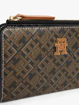 Billetera plegable Tommy Hilfiger con estampado de monograma en tonos marrones y negros. Cuenta con múltiples ranuras para tarjetas, compartimento para billetes y bolsillo exterior con cremallera para monedas.