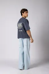 Remera gris oscuro de corte boxy, con mangas cortas y cuello redondo. Cuenta con un diseño gráfico frontal con líneas blancas y la palabra 'CONCEPT' estampada.