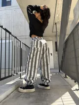 Pantalón de jean con diseño de rayas verticales en tonos gris y blanco, de corte ancho y relajado.