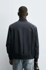 Cazadora de corte regular confeccionada en tejido técnico repelente al agua. Presenta cuello subido, manga larga con puños de rib, bolsillos laterales de vivo y cierre frontal con cremallera.