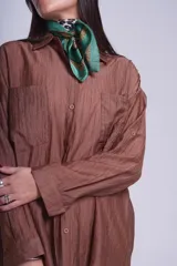 Camisa negra de tela traslúcida con cuello clásico, cierre frontal con botones y dos bolsillos de parche en el pecho.