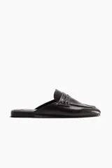 Mules estilo mocasín color marrón oscuro, con diseño destalonado, punta redondeada y tira frontal característica del modelo penny loafer.