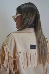 Campera color beige de gamuza sintética con flecos en mangas, espalda y ruedo.